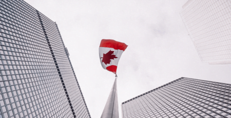 A Step by Step Guide to Federal Incorporation in Canada - Canadian flag between buildings against a white sky